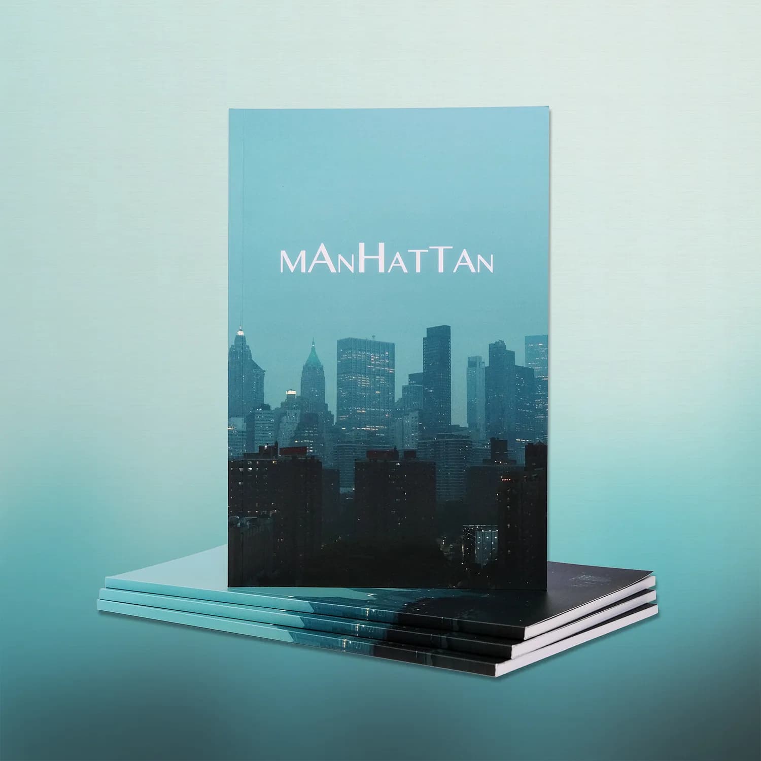 Manhattan Volume 1 standing upright on a stack of copies, its cover a misty Manhattan skyline